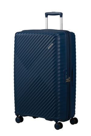 A navy blue hardshell suitcase with a textured diagonal ribbed pattern, featuring an extended telescopic handle and four spinner wheels, shown on a plain white background.