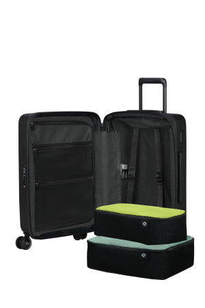 Black open suitcase with a green packing cube inside on a white background